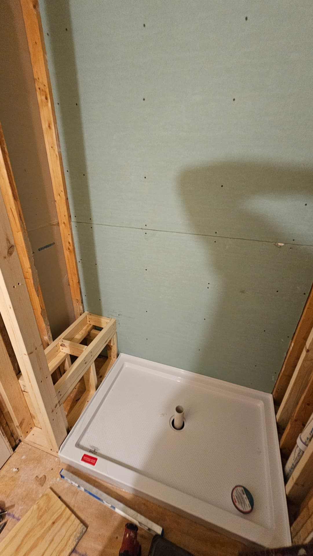 Shower pan set and green board hung, with a framed bench ready for tile