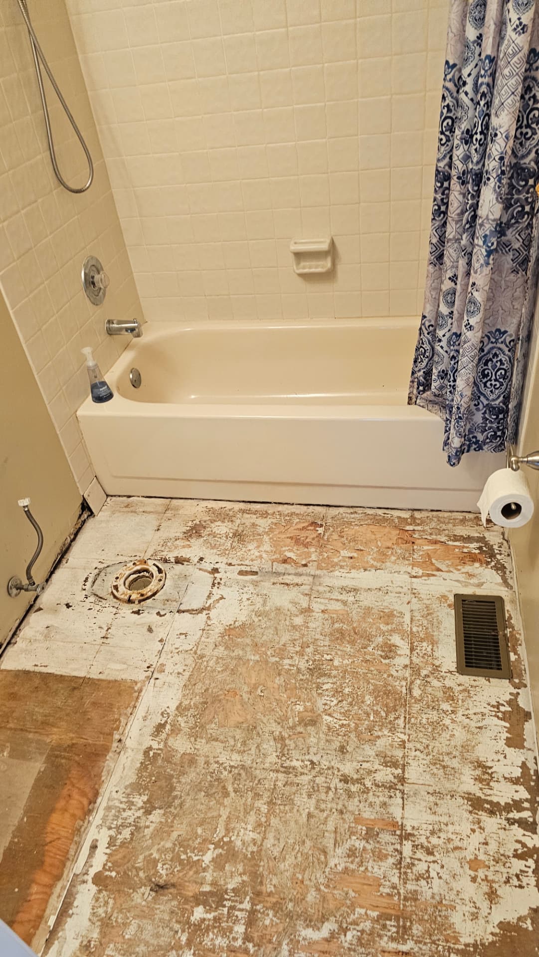 Original bathroom with dated square wall tile and the floor stripped to bare subfloor
