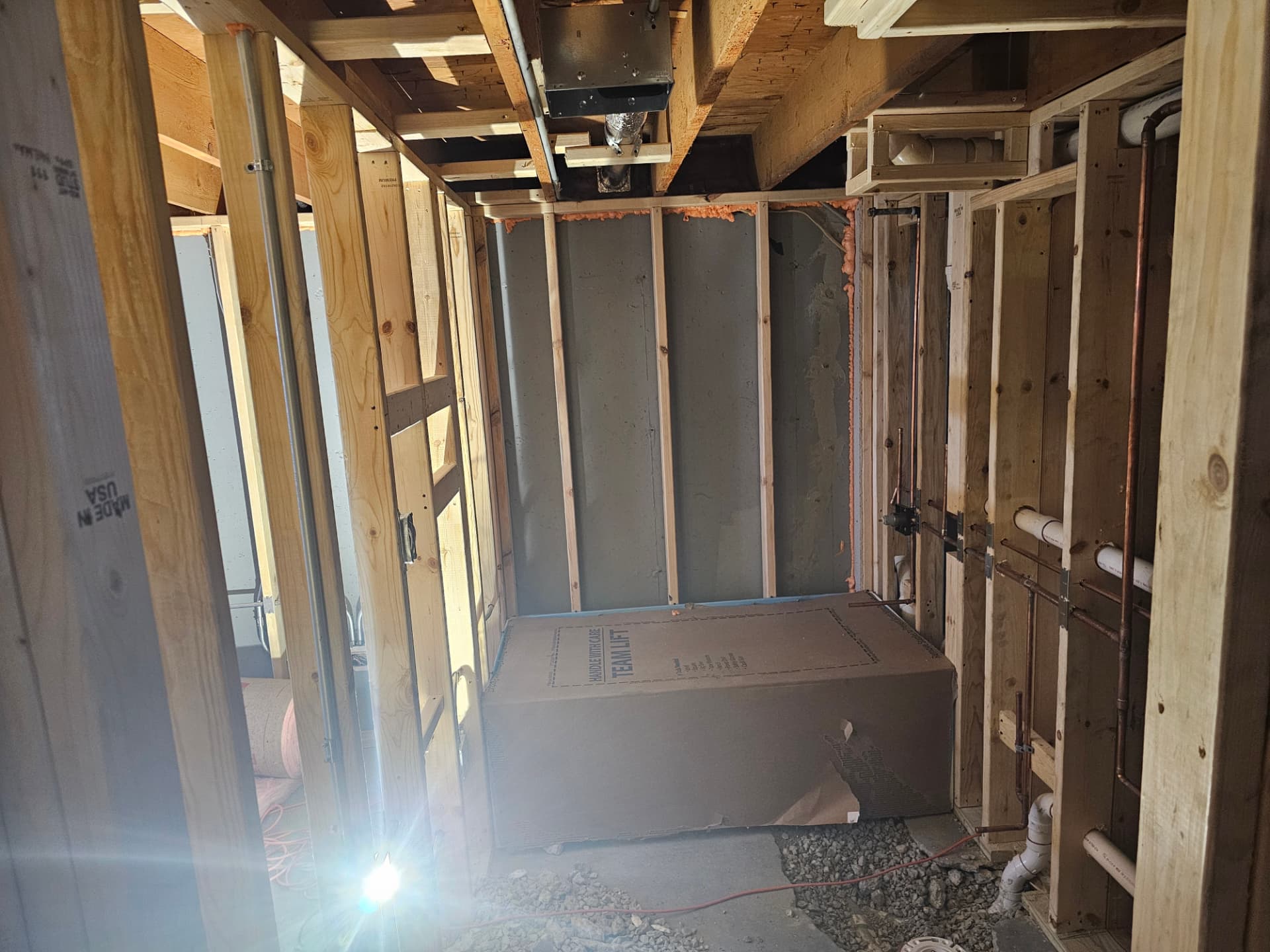 Bathroom rough-in with stud framing, copper supply lines and drain piping in place
