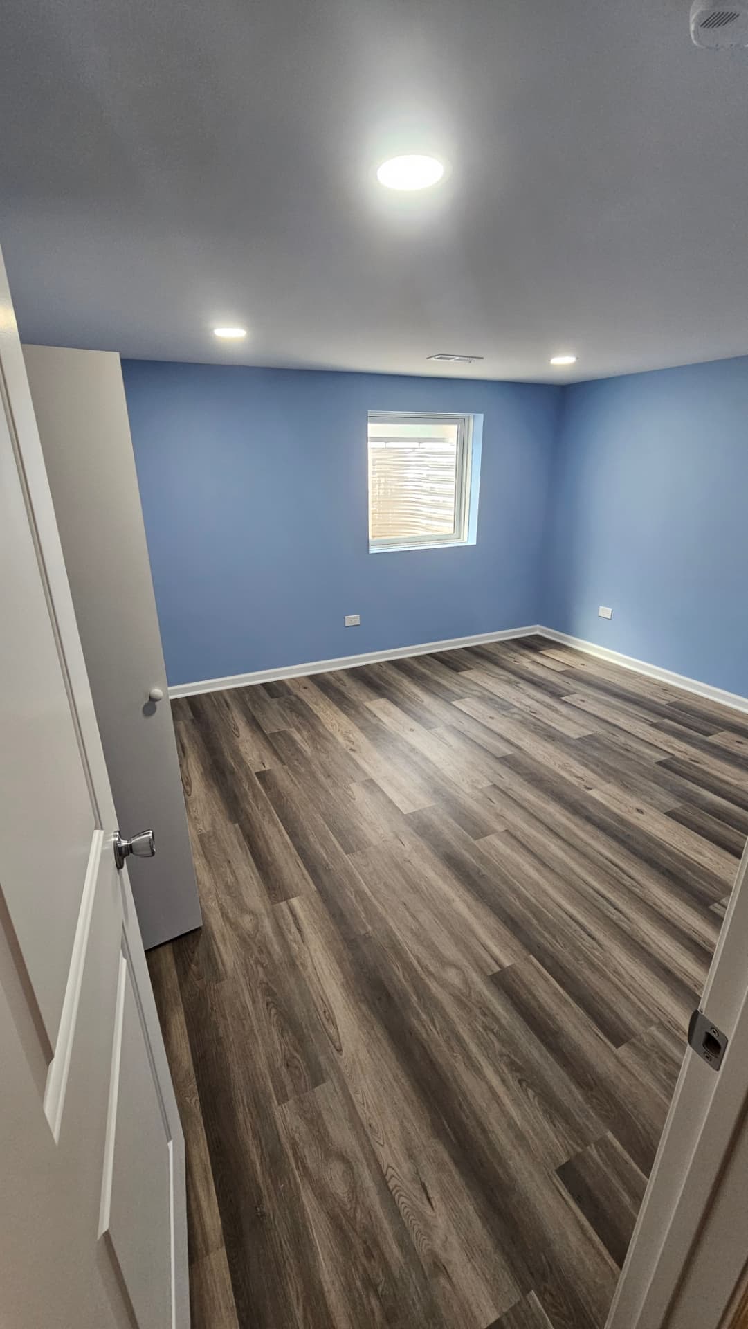 Second view of the finished bedroom showing the window wall and recessed lighting